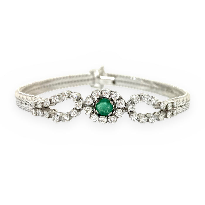 White gold vintage bracelet with a round emerald center flanked by looping diamond swirls